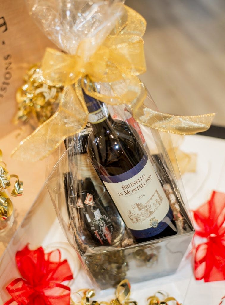 A beautifully wrapped gift basket from the Blue Goat, including a bottle of wine, a glass, and accoutrements.