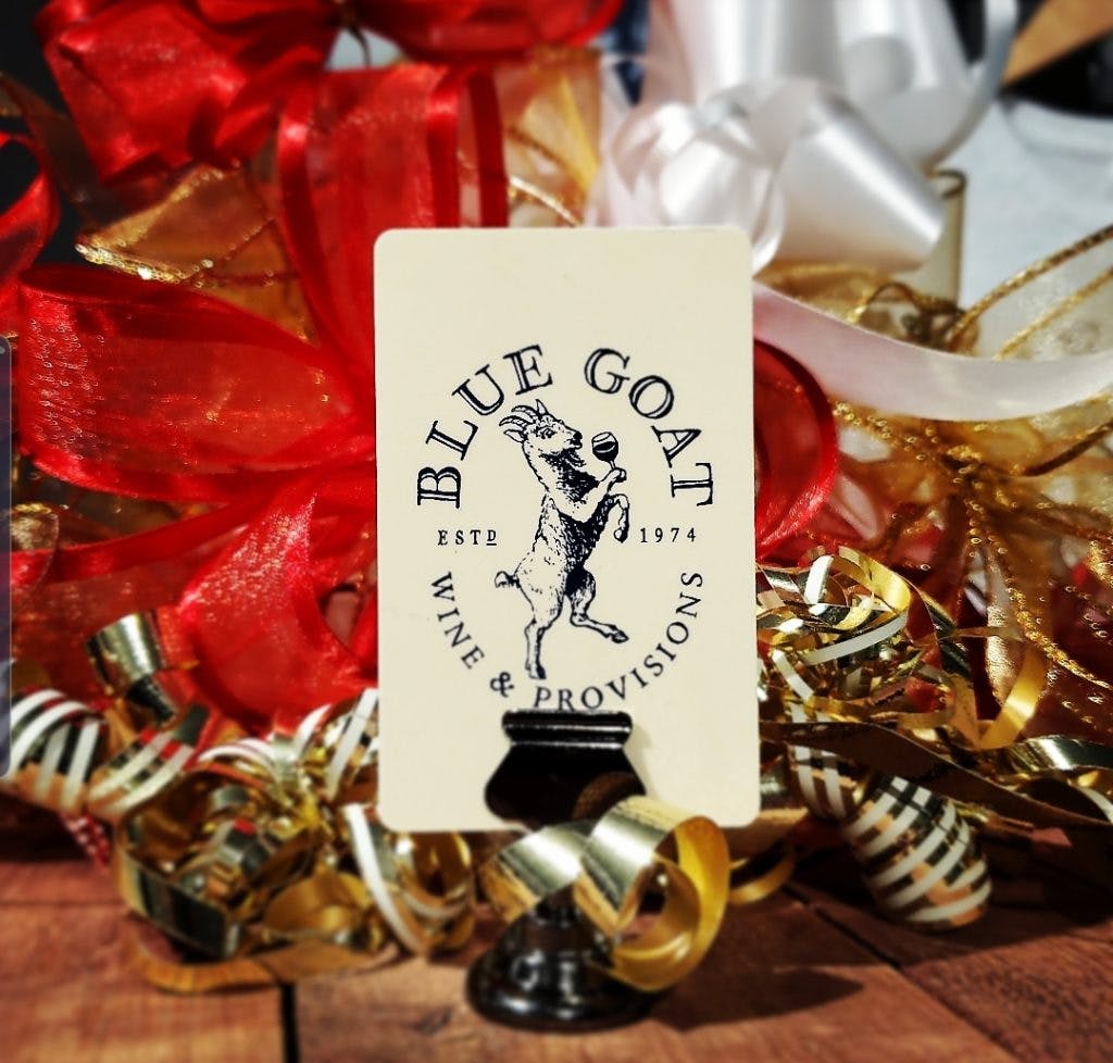 A Blue Goat card label sitting in front of an extravagantly packaged gift basket.