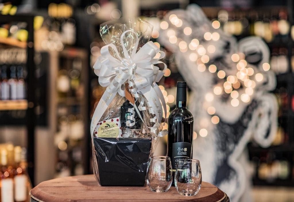 A Blue Goat gift basket sitting next to another bottle of wine and two Blue Goat wine glasses.